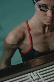 Close-up of a focused female swimmer at the poolside. Ready for a swim.
