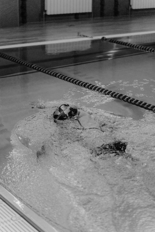Free Swimmer practicing strokes in an indoor swimming pool, captured in black and white. Stock Photo