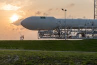 日落时分，航天飞机停在发射台上，人们在附近行走