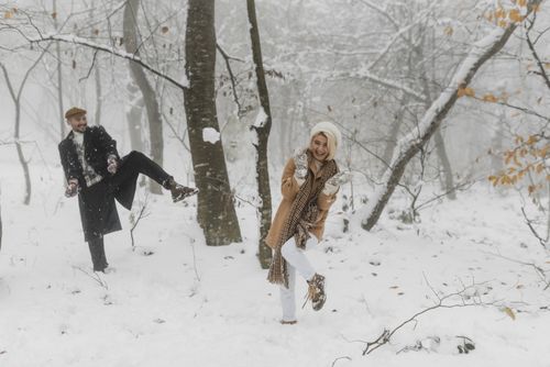 Free A cheerful couple playing in a snowy forest, embodying love and fun in wintertime. Stock Photo