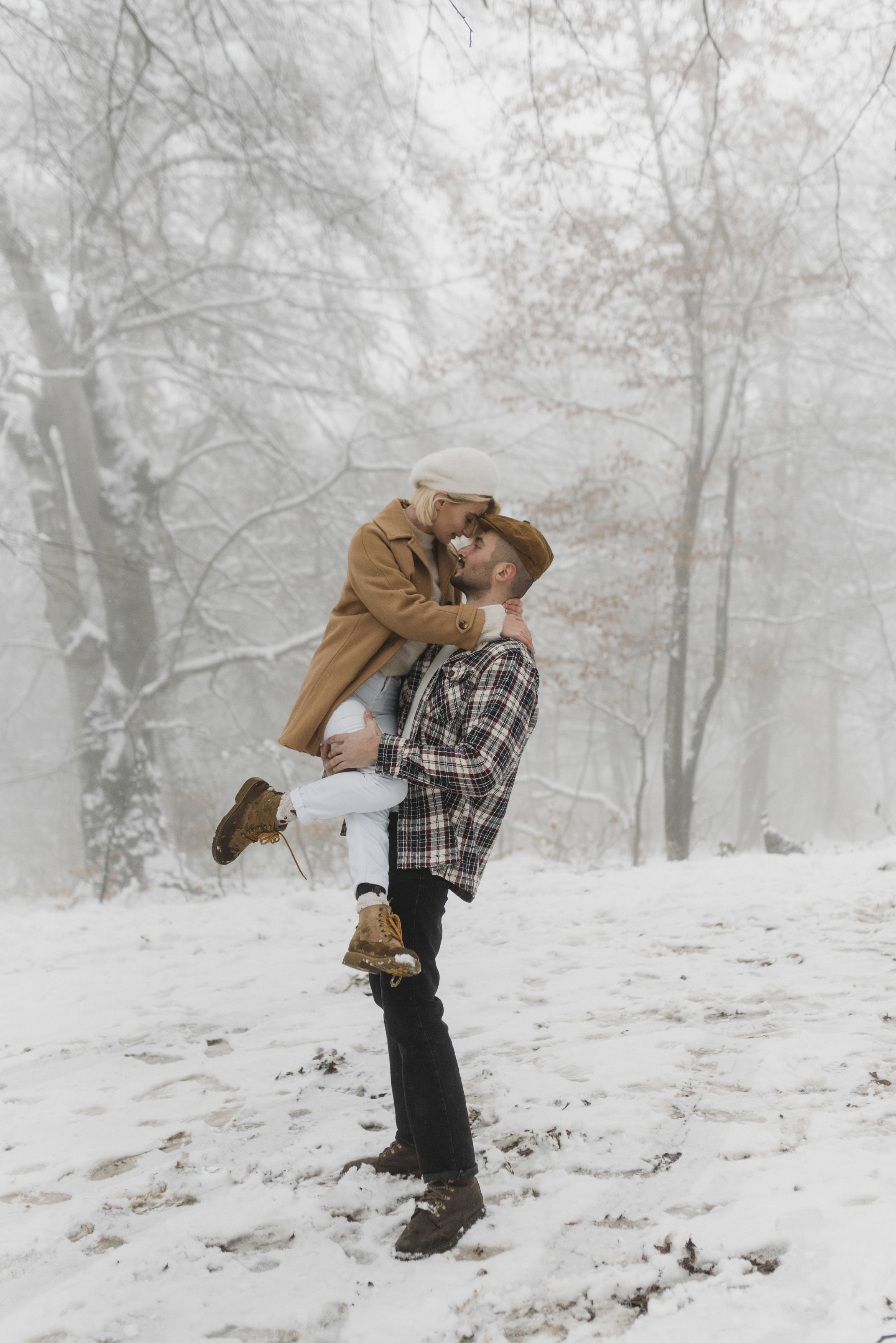Couple embracing in a snowy forest, capturing love and warmth amidst winter chill.
