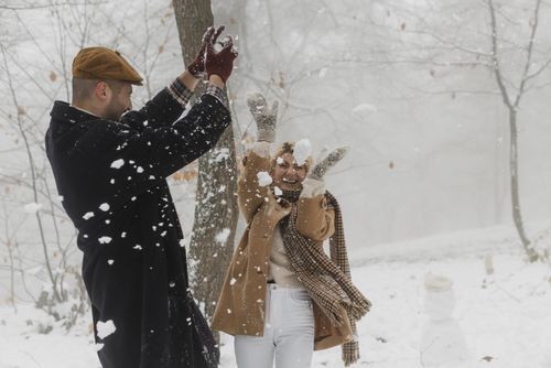 Free Happy couple playing in the snow, expressing love and joy during a winter day. Stock Photo