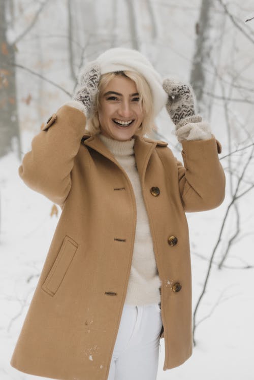 Wanita Tersenyum Dengan Mantel Coklat Berdiri Di Tanah Tertutup Salju