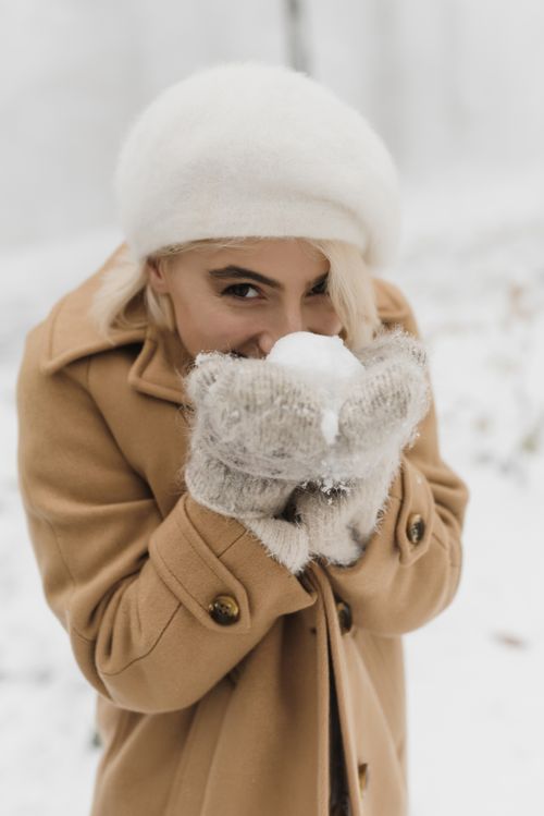 Free Young woman in winter clothing holding a snowball, enjoying the snowy outdoors. Stock Photo