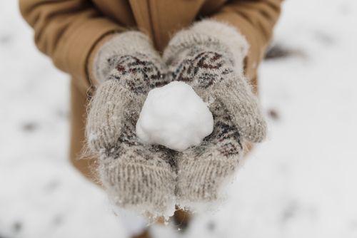Free Close-up of hands in mittens holding a snowball on a snowy winter day. Stock Photo