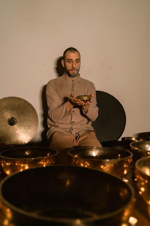 Free A man meditates with a singing bowl indoors, surrounded by instruments, promoting relaxation and healing. Stock Photo