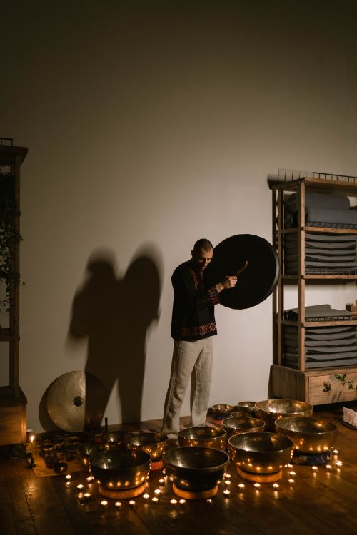 Free A man performs calming music in a dimly lit room with Tibetan singing bowls and candles. Stock Photo