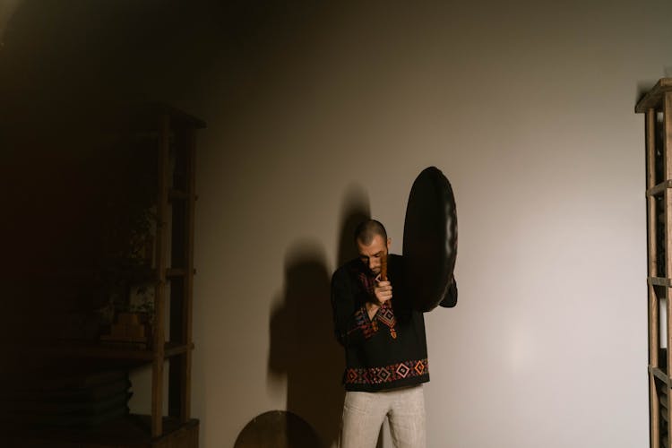 Man In Black Tassel Holding A Gong