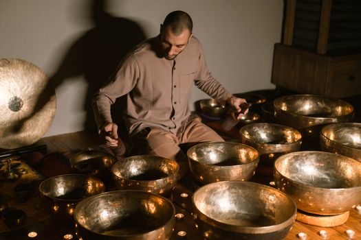 An adult man meditates with Tibetan singing bowls for relaxation and healing.