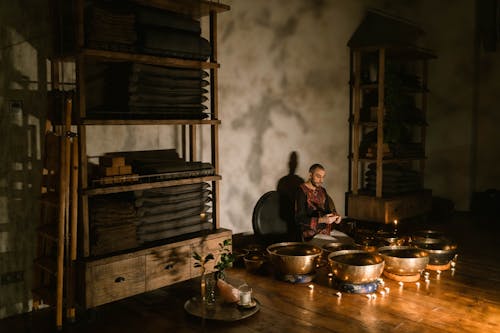 A Man Meditating Surrounded by Tibetan Singing Bowls and Lighted Candles