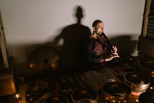 Free Man playing flute surrounded by Tibetan singing bowls in a serene setting. Stock Photo