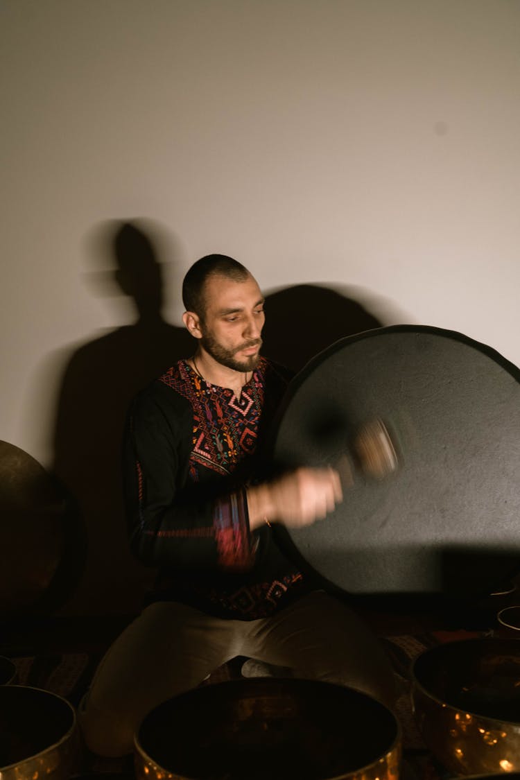 A Man In Black Tassel Hitting A Gong