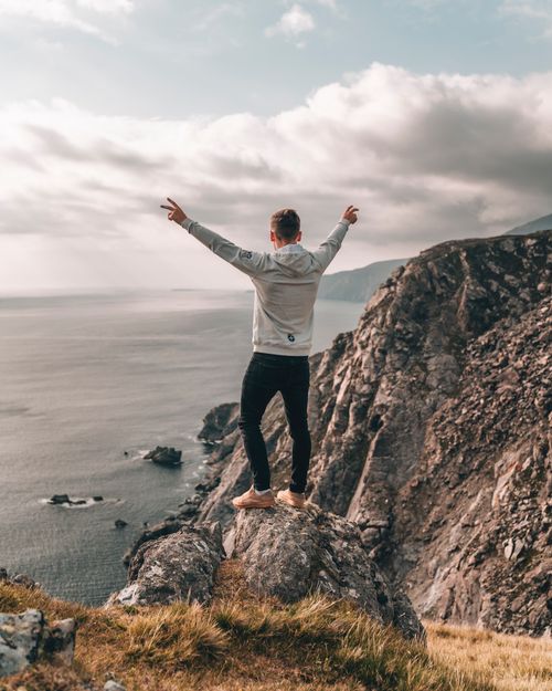 Free Man enjoys breathtaking view from rocky cliff along Ireland's rugged coastline, embracing nature. Stock Photo