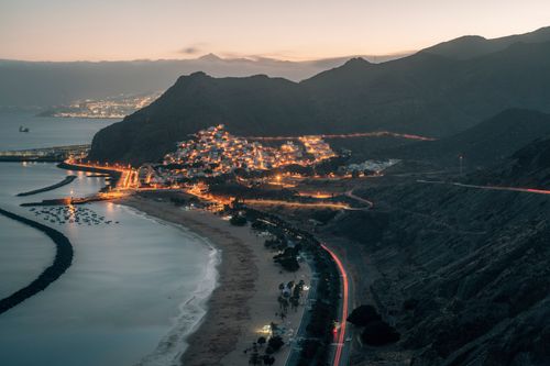 Free A scenic aerial view of a Tenerife town with glowing lights and coastal landscape at dusk. Stock Photo