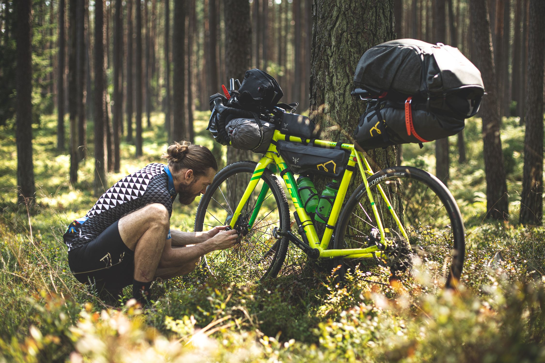 Bikepacking bike resting at a remote campsite with bags visible on frame and handlebars