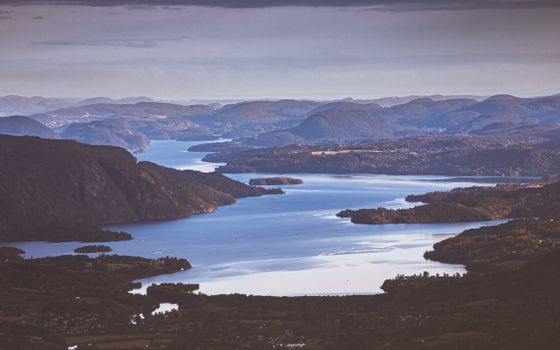 Stunning aerial view of a tranquil Norwegian fjord at twilight, surrounded by majestic mountains and lush landscapes.