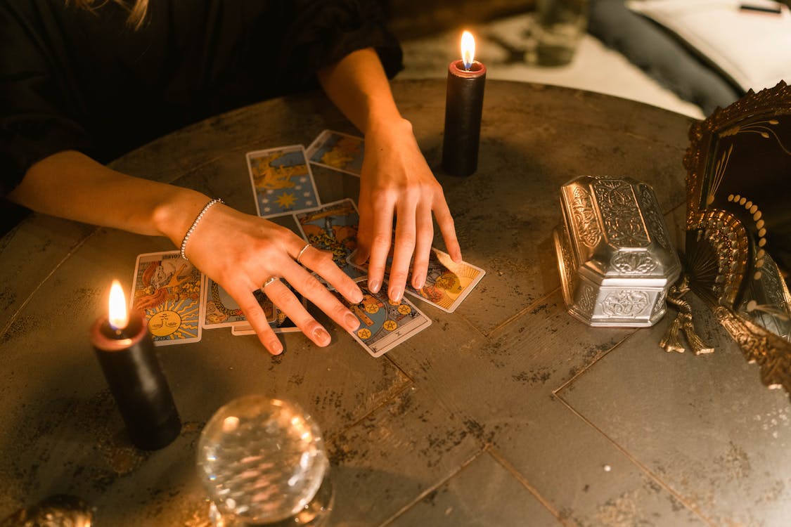 Woman reading tarot cards on a table with lit candles.