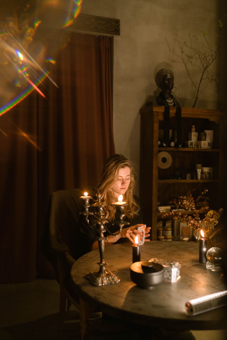 The reader holding her cards at the candlelit studio table