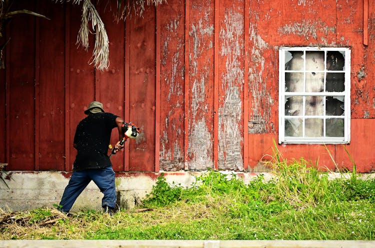 A Man Cutting The Grasses In Front Of A House