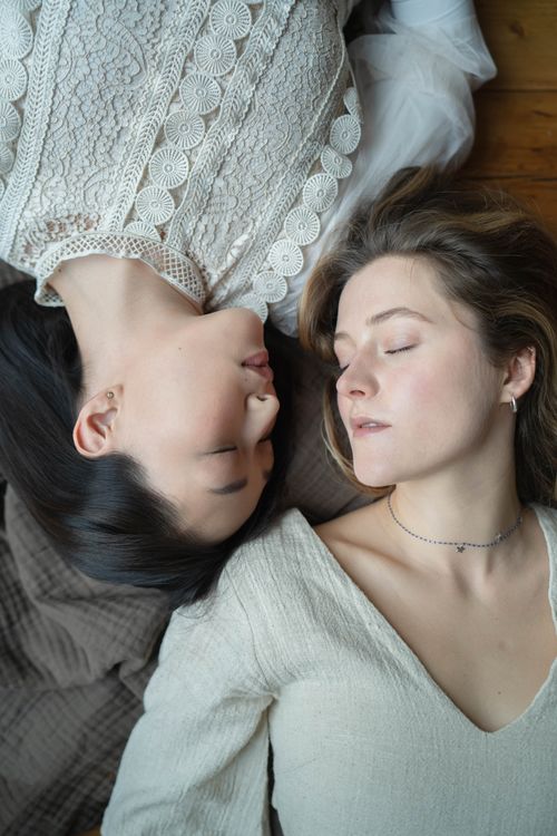 Free Two women with closed eyes lying together peacefully indoors. Harmony and tranquility captured. Stock Photo