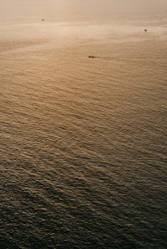 A tranquil view of the ocean at sunset with small boats in Bali, Indonesia.
