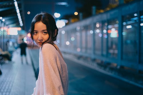 晚上街與明亮的燈光的年輕亞裔女子