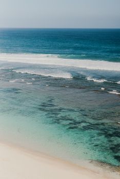 Explore the tranquil beauty of Bali's coastline with this aerial beach photograph showcasing clear waters and a serene horizon.