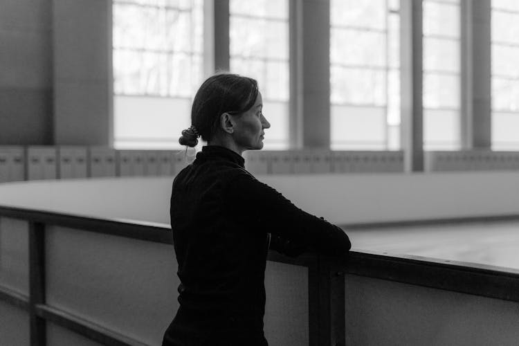 Side View Of Woman Standing Beside Fence In Grayscale Photography 