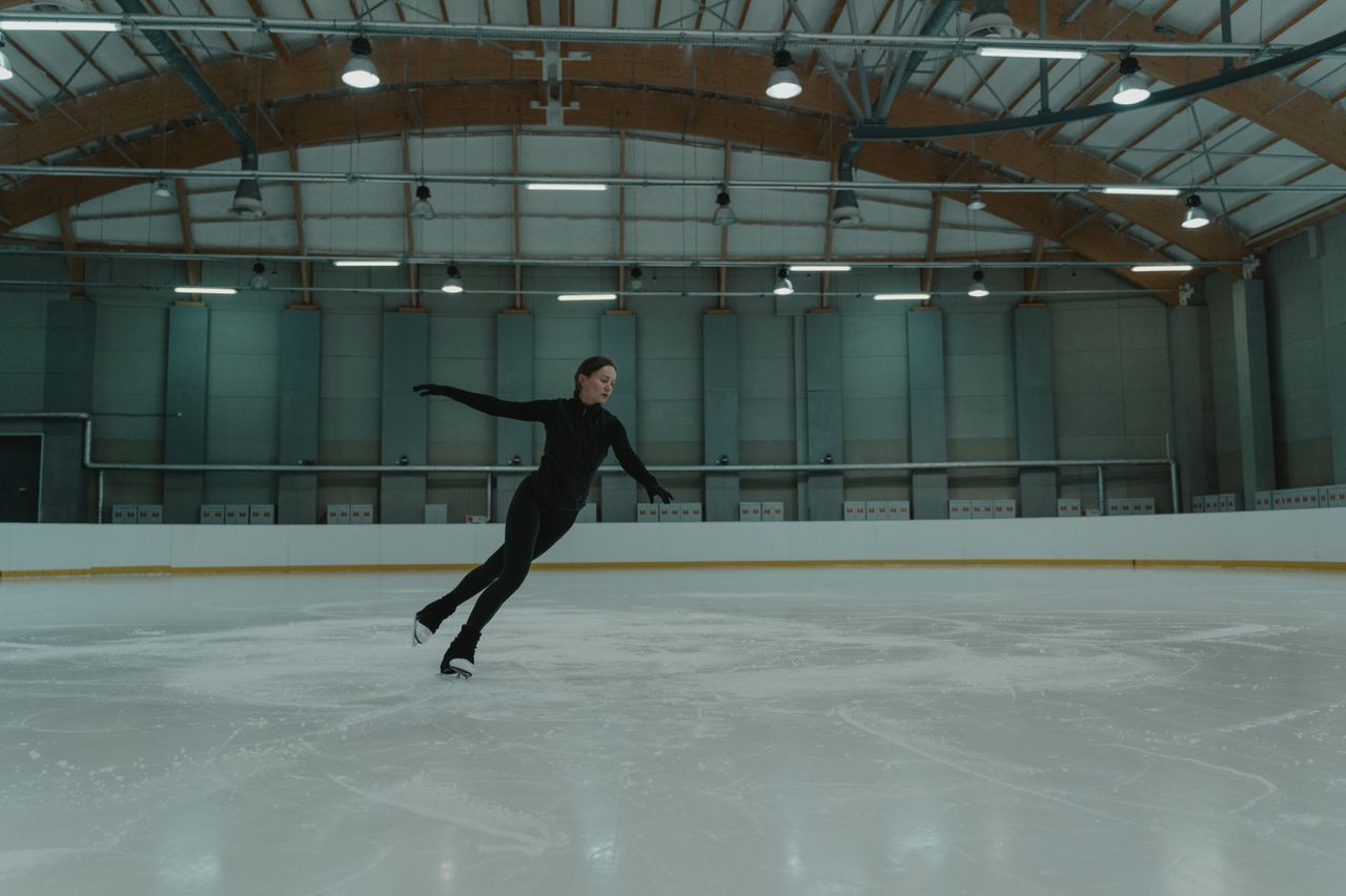 a female figure skater practices on an indoor ice rink showcasing skil