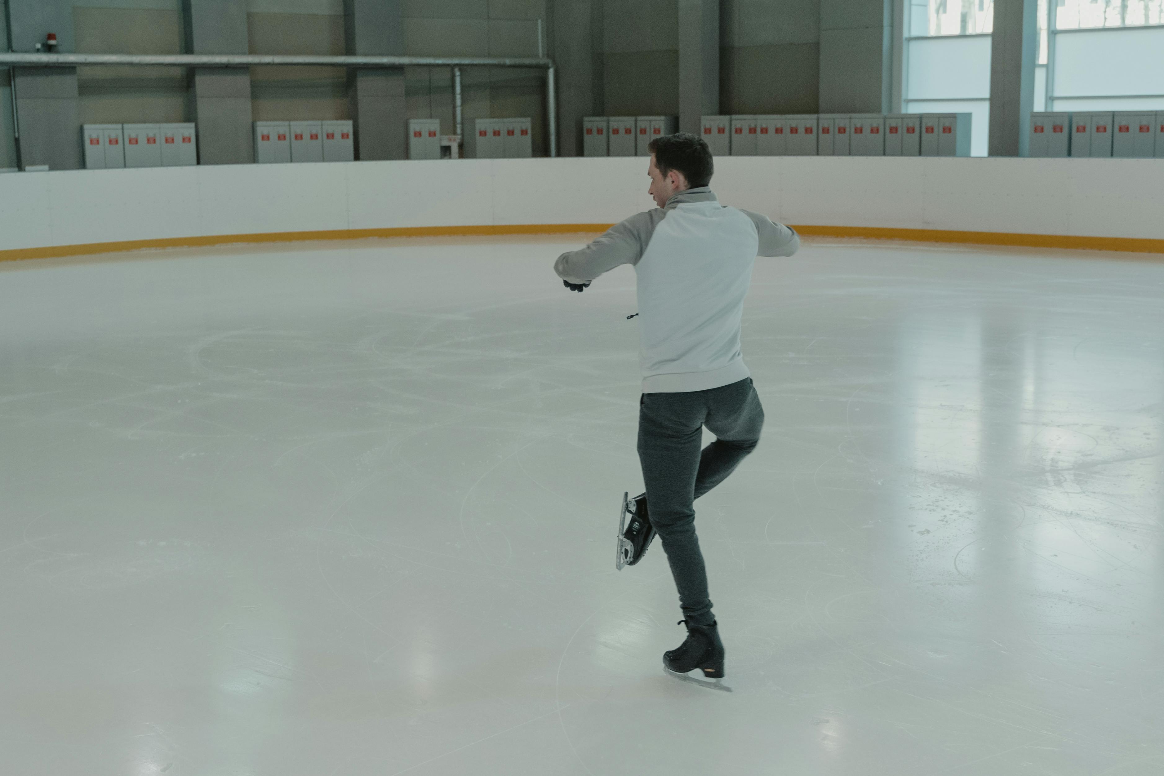 man in white long sleeve shirt and black pants playing ice hockey