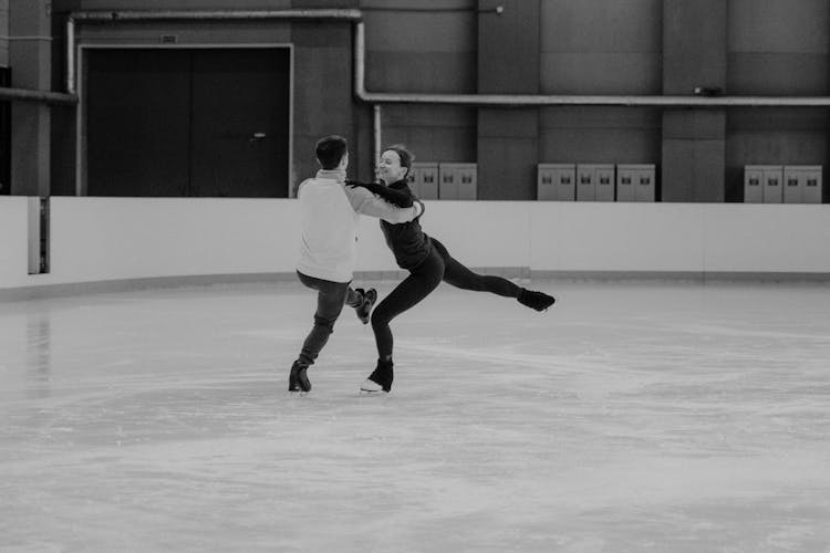  A Grayscale Photo Of A Couple Skating Together