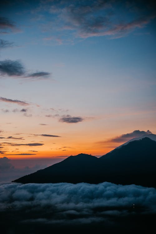 Gratis Silueta De Montañas Bajo El Cielo Nublado Durante La Puesta De Sol Foto de stock