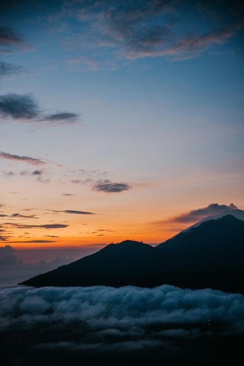 Free Serene sunset view over Bali's mountain silhouette with vibrant sky and low-lying clouds. Stock Photo