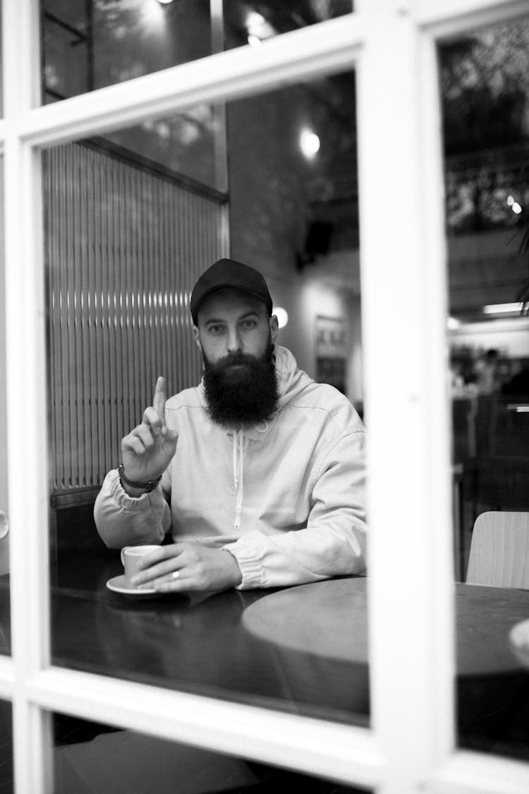 Hipster Man With Cup Of Coffee In Cafeteria