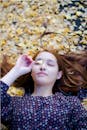 Portrait of Teenage Girl Lying on Ground Covered in Fallen Leaves
