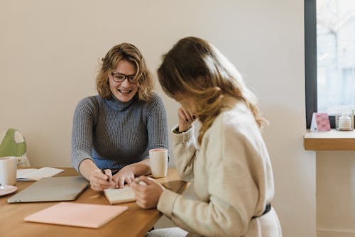 Women Sitting at the Table and Writing on Paper 