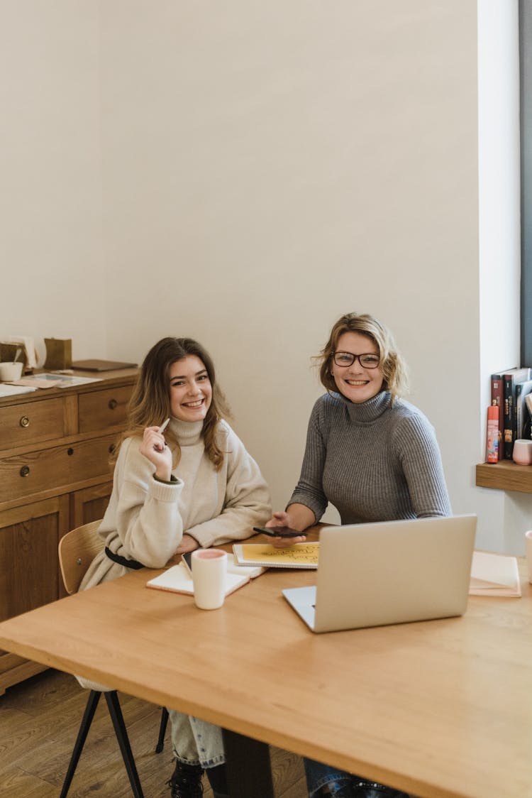 Two Smiling Women At Desk With Laptop