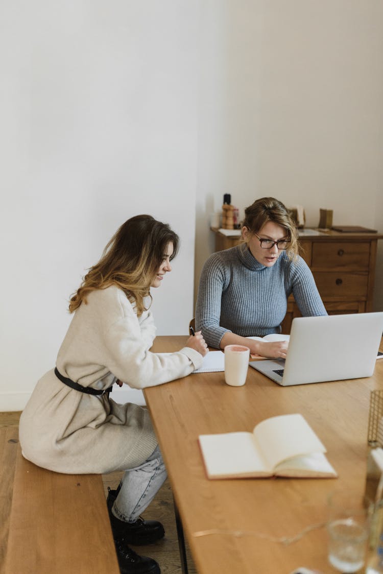 Women Sitting At The Table Working On A Laptop