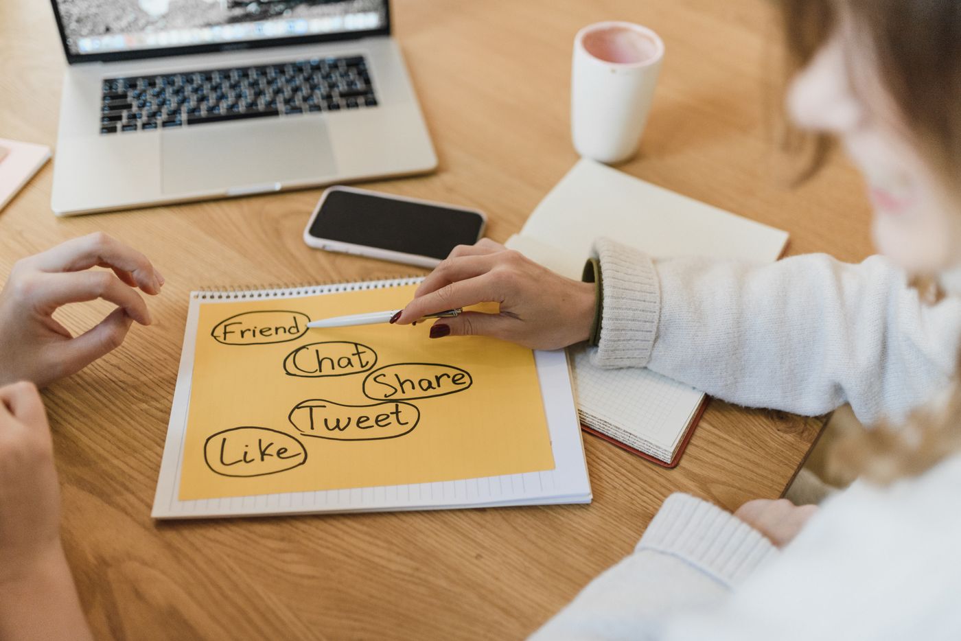 Two people planning a social media content calendar with a laptop and phone