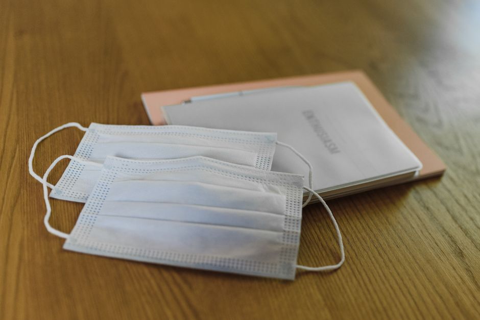 State Health Officials Mandate Emergency Closures to Safeguard Palm Beach’s Dining Industry – April 12 2 Two face masks and documents on a wooden table, representing healthcare and safety. | BocaVibe