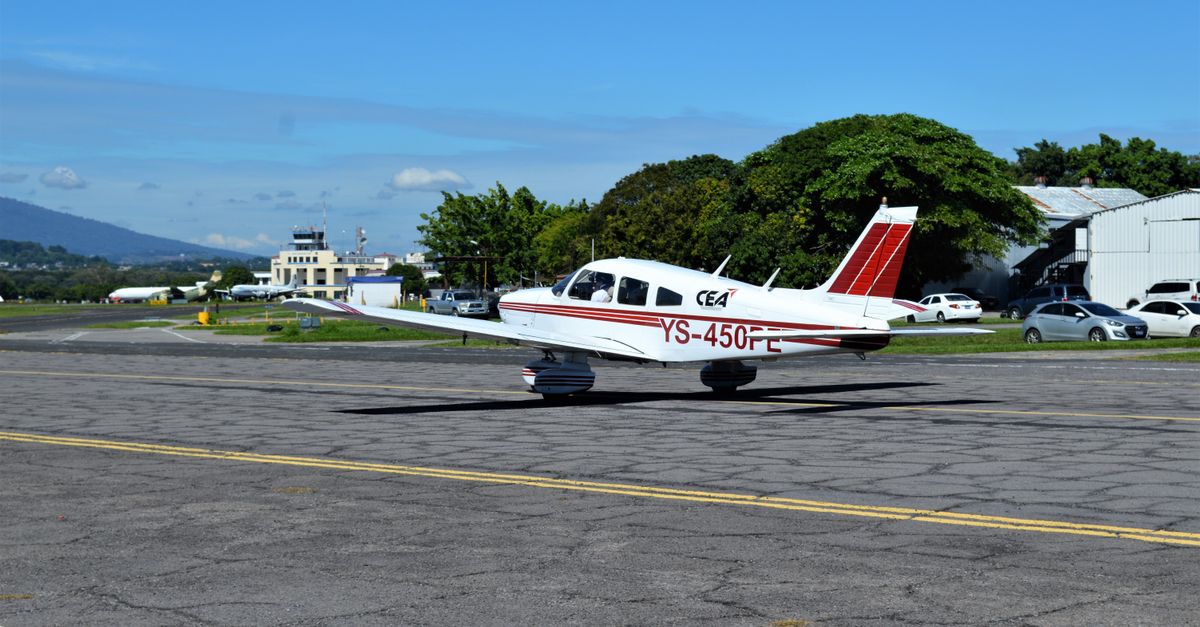 Small airplane on tarmac at local airport, ready for takeoff under clear blue sky.