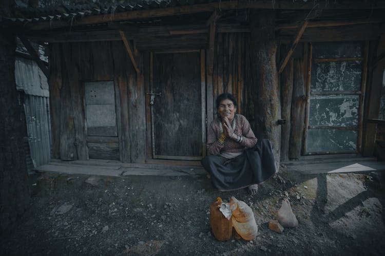 Smiling Indian Woman With Praying Hands Near Old House