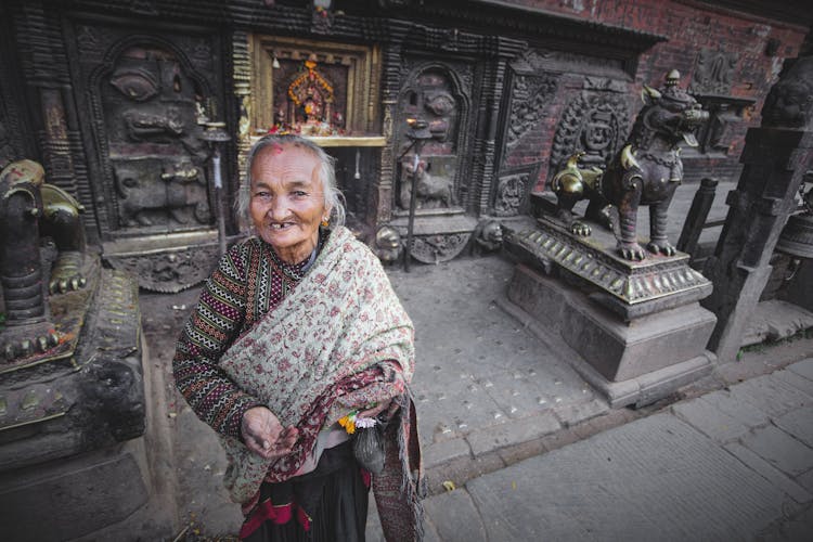 Smiling Senior Indian Woman On City Street Between Sculptures