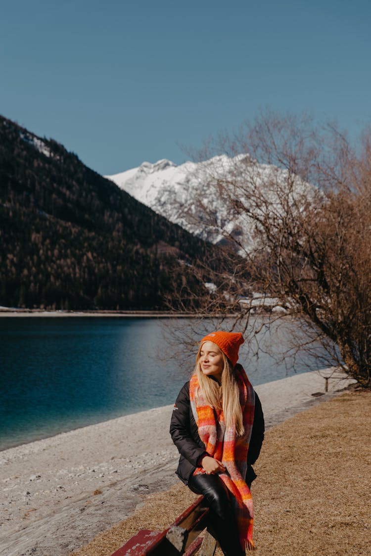 Woman Sitting On A Bench Beside A Lake