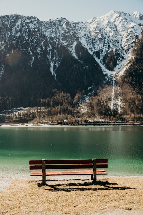 免費 湖和山附近的棕色木製長椅 圖庫相片