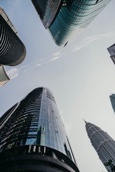 Low angle view of modern skyscrapers in Kuala Lumpur with Petronas Twin Towers visible.
