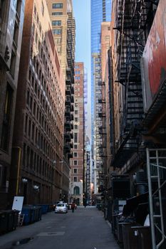A narrow alleyway flanked by towering buildings, showcasing urban architecture.