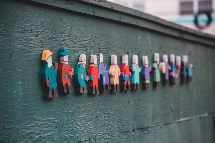 Wooden Figures Of People Placed On Wooden Wall On Street