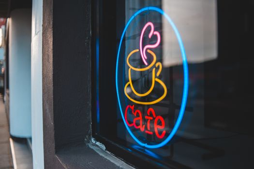 Bright glowing neon inscription cafe on window of urban building on avenue in daytime
