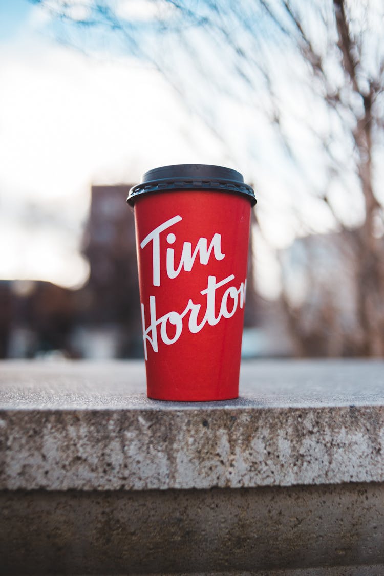 Red Paper Cup With A Drink On A Concrete Wall 